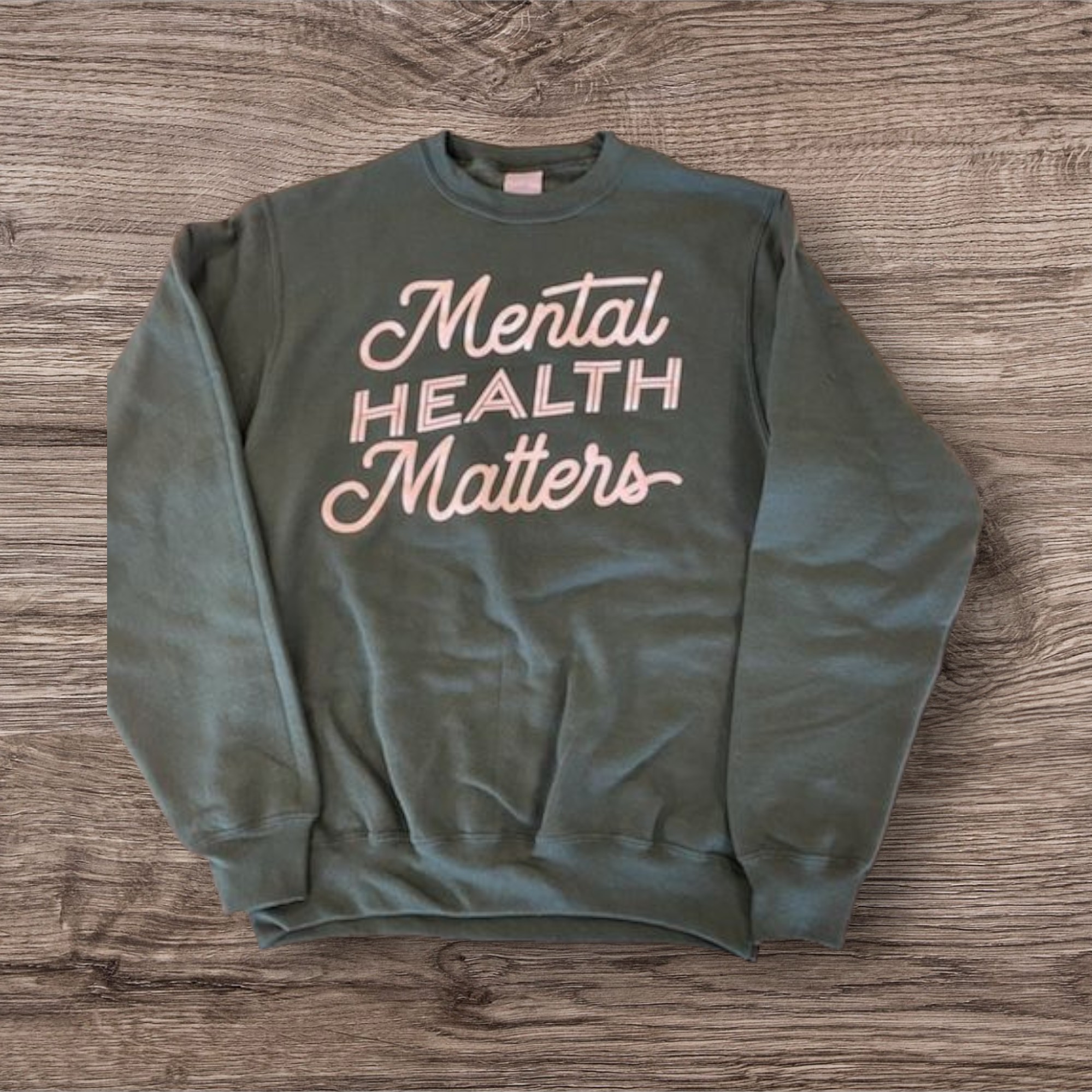 Sage green crewneck sweatshirt with a screen-printed pink script design, an example of a screen-printable crewneck sweatshirt