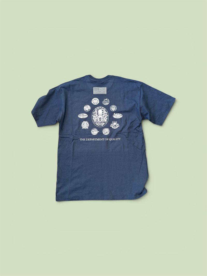 Heather navy T-shirt with a full-back white screen print featuring an American flag, a ring of badge icons and the text 'The Department of Quality'